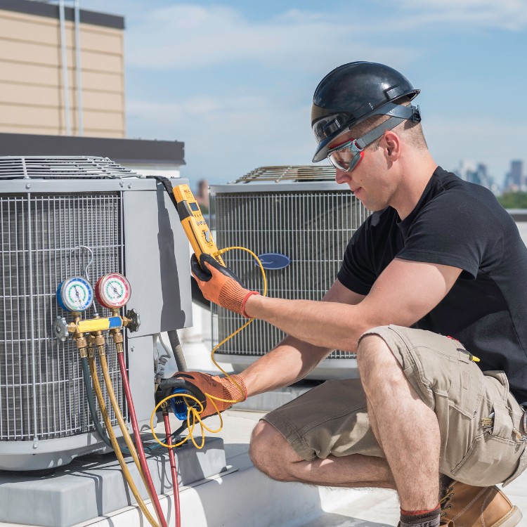 Technician servicing a rooftop commercial HVAC system Technician servicing a rooftop commercial HVAC system
