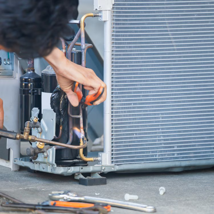 Technician repairing the internal components of an air conditioning system Technician repairing the internal components of an air conditioning system